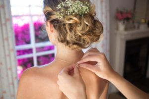 bridesmaid-fastening-bride-chain-in-dressing-room.jpg